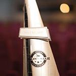 A gold, triangular statuette with the words Hall of Fame overlaid on the Full Sail University logo.